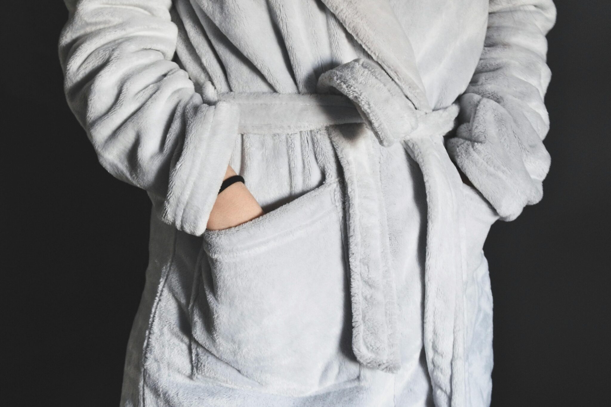 Close-up of a soft grey fleece bathrobe with hands tucked in pockets, creating a cozy feel.